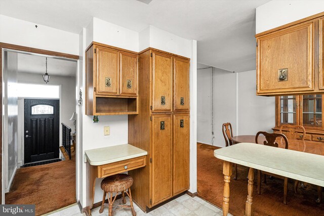 kitchen featuring light countertops, light floors, light carpet, and brown cabinets