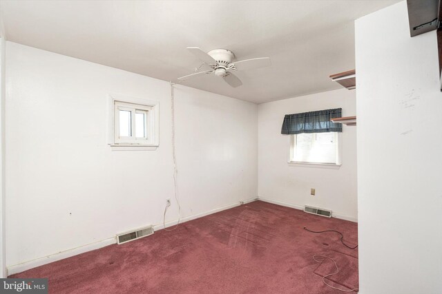 carpeted empty room with a healthy amount of sunlight, ceiling fan, and visible vents