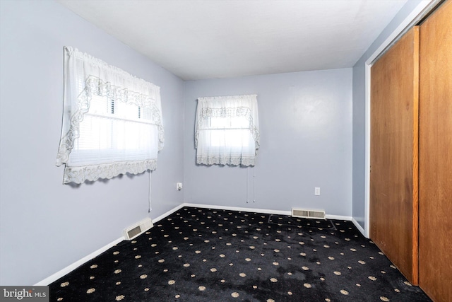 empty room with baseboards, visible vents, and carpet