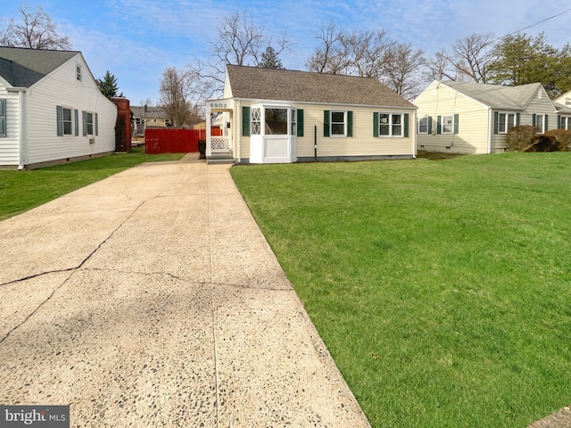 view of front of property with roof with shingles, concrete driveway, and a front yard