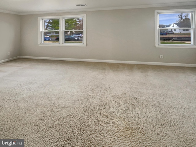 carpeted spare room with baseboards, visible vents, and crown molding