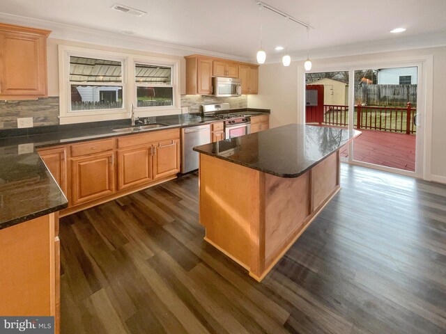 kitchen featuring a kitchen island, a sink, stainless steel appliances, and crown molding