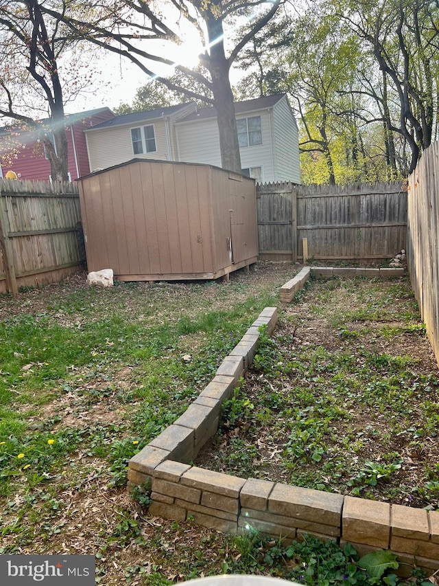 view of yard featuring a storage shed, an outbuilding, and a fenced backyard