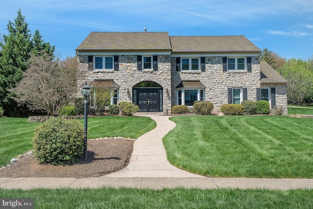 view of front facade with a front yard and stone siding