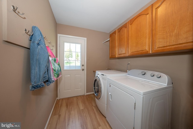 washroom featuring baseboards, light wood-type flooring, cabinet space, and washer and clothes dryer