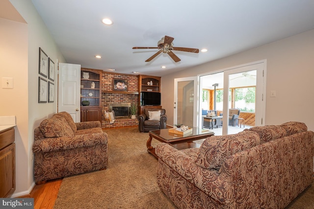 living room with a ceiling fan, built in features, a fireplace, wood finished floors, and recessed lighting