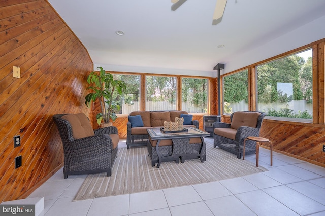 tiled living area with ceiling fan and wood walls