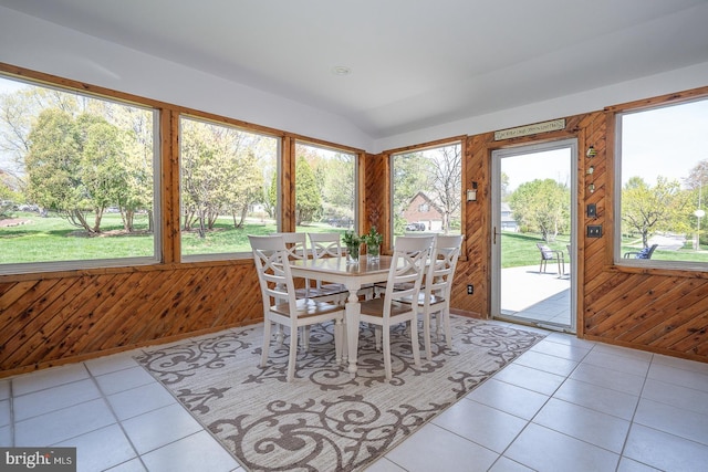 sunroom / solarium featuring wooden walls, tile patterned floors, and vaulted ceiling