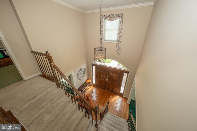 entryway with baseboards, an inviting chandelier, ornamental molding, and wood finished floors