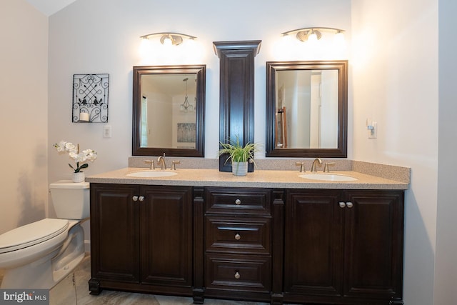bathroom with double vanity, toilet, and a sink