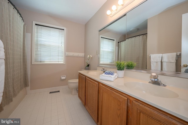 bathroom with tile patterned flooring, a sink, double vanity, and toilet