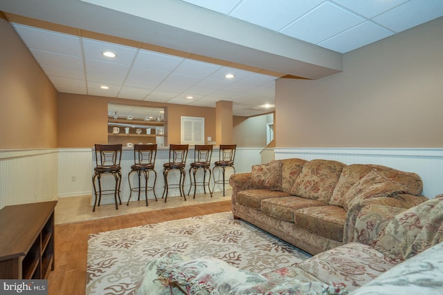 living room featuring a paneled ceiling, recessed lighting, wood finished floors, and a wainscoted wall
