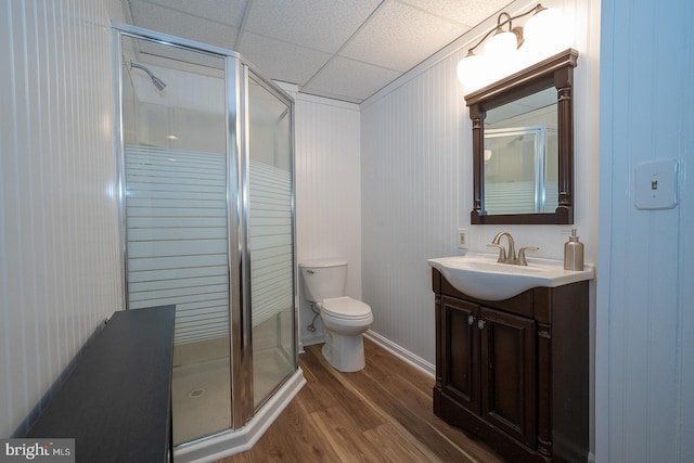 bathroom with toilet, a shower stall, wood finished floors, and vanity