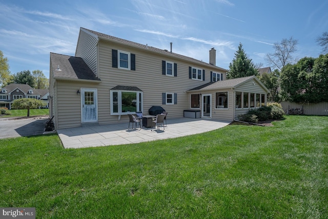rear view of property with a patio, a lawn, fence, and a chimney