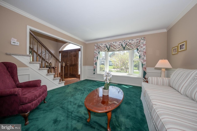 carpeted living area with a wainscoted wall, ornamental molding, a decorative wall, and stairs