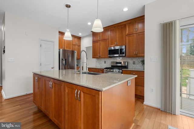 63 Woodleigh Ln, Stafford, VA 22556 - kitchen with decorative backsplash, a sink, light wood-style flooring, appliances with stainless steel finishes, and brown cabinetry