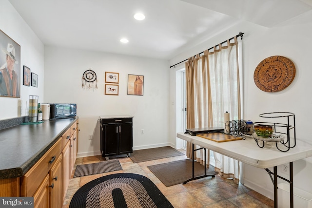 interior space with black microwave, baseboards, dark countertops, and recessed lighting