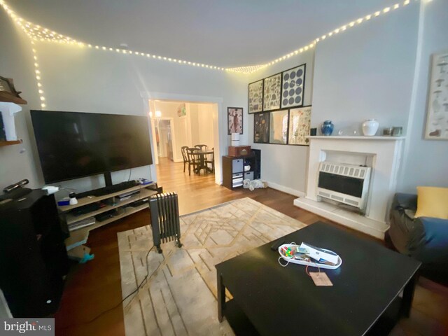living room featuring heating unit, a fireplace, and wood finished floors