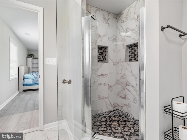 ensuite bathroom with a stall shower, wood finished floors, baseboards, and connected bathroom