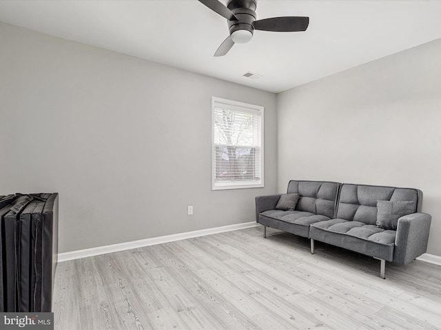 living area with visible vents, light wood-style flooring, ceiling fan, and baseboards