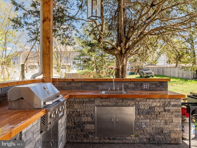 view of patio with a sink, fence, exterior kitchen, and area for grilling