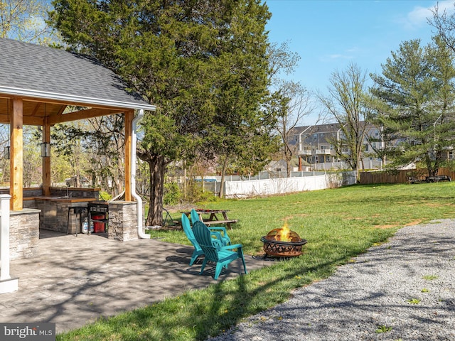 view of yard with an outdoor fire pit, a patio, fence, and exterior kitchen
