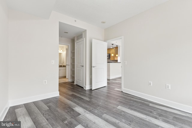 unfurnished room featuring visible vents, baseboards, and wood finished floors