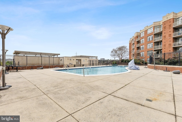 community pool with a patio area and fence