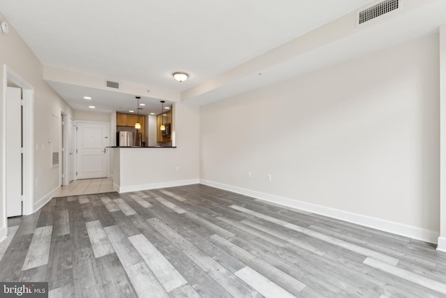 unfurnished living room with baseboards, visible vents, and wood finished floors