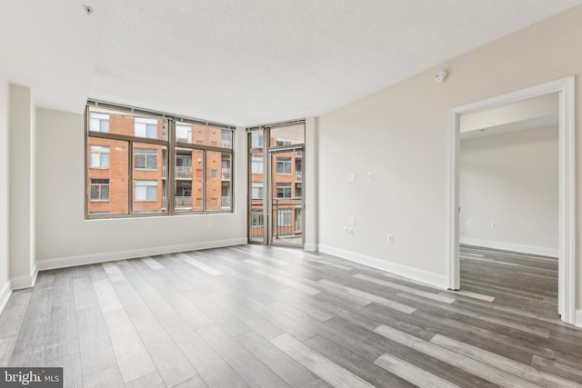 empty room with baseboards, a textured ceiling, and wood finished floors