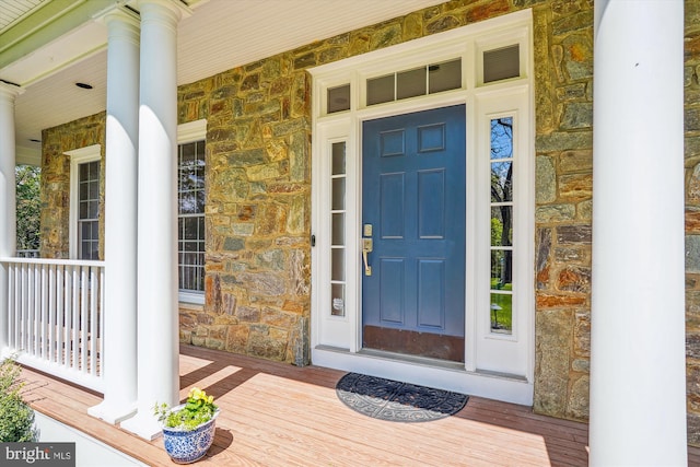 property entrance featuring stone siding and a porch