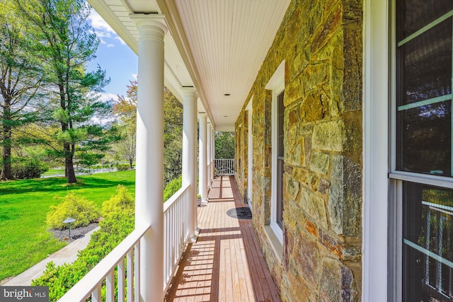 wooden deck with a lawn and covered porch
