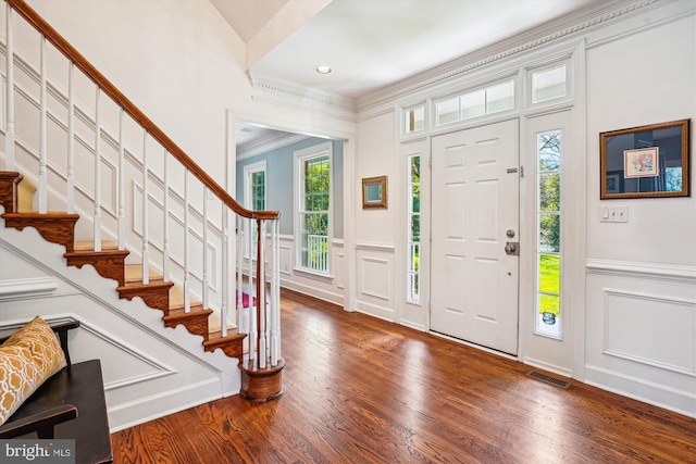 entryway featuring wood finished floors, stairway, and a decorative wall