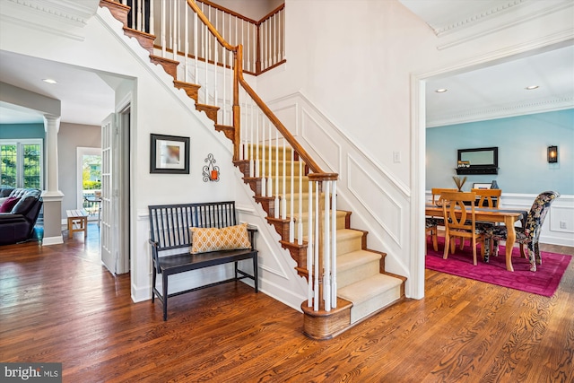 stairway with crown molding, wood finished floors, recessed lighting, and a decorative wall