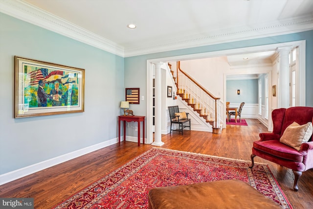 living area with ornamental molding, wood finished floors, and ornate columns