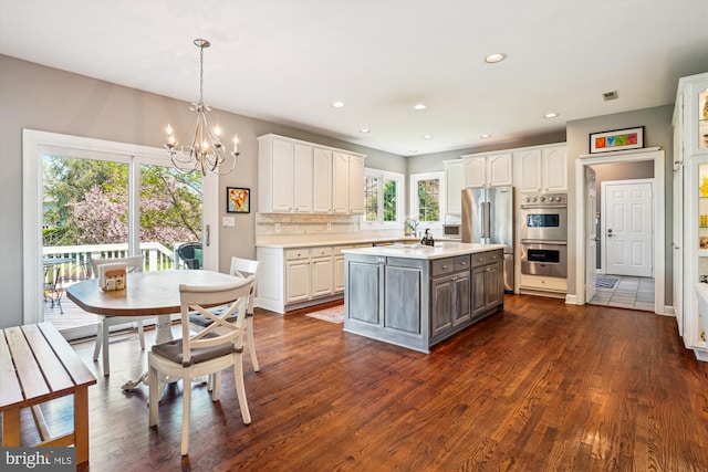 kitchen featuring dark wood-type flooring, light countertops, appliances with stainless steel finishes, and white cabinetry