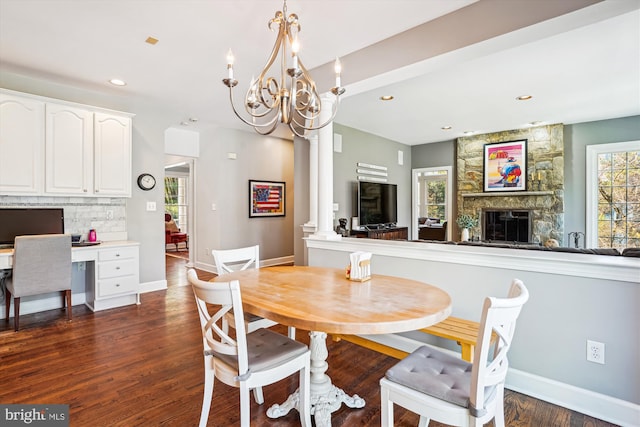 dining area featuring a notable chandelier, baseboards, dark wood-style flooring, and a fireplace