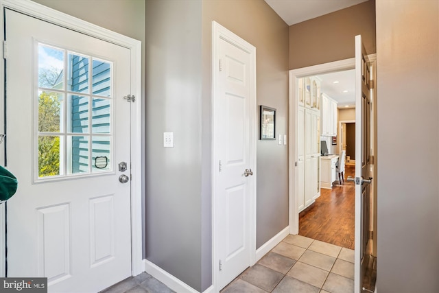 doorway to outside with baseboards and light tile patterned flooring