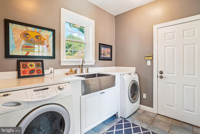 clothes washing area with a sink, light tile patterned floors, cabinet space, baseboards, and independent washer and dryer
