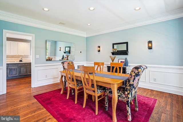 dining space featuring wainscoting, wood finished floors, recessed lighting, and crown molding