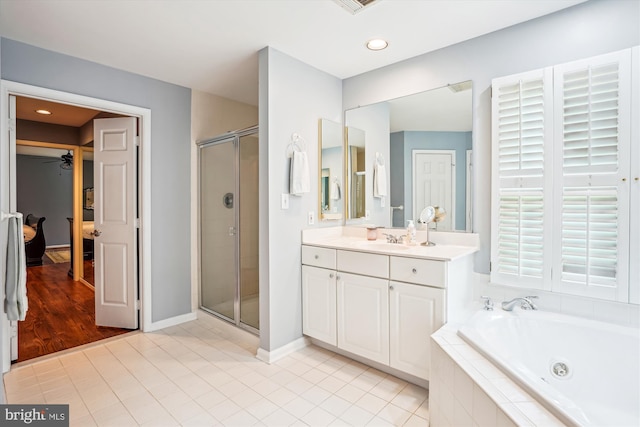 bathroom with a shower stall, vanity, a jetted tub, baseboards, and tile patterned flooring