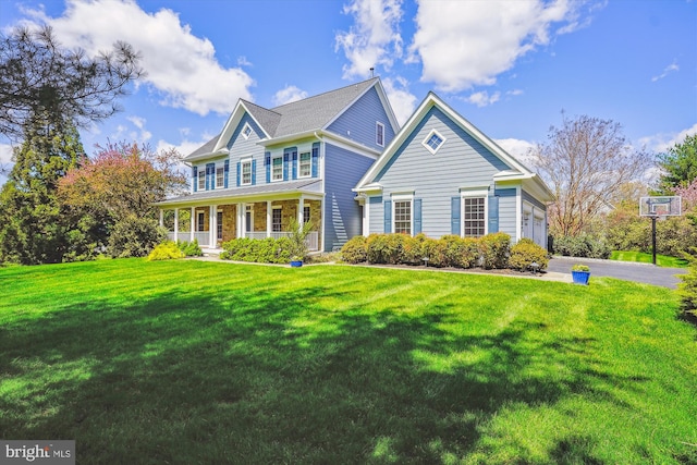 colonial home with a front lawn, aphalt driveway, a porch, and an attached garage