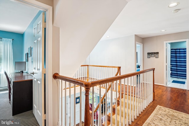 corridor featuring recessed lighting, wood finished floors, baseboards, and an upstairs landing