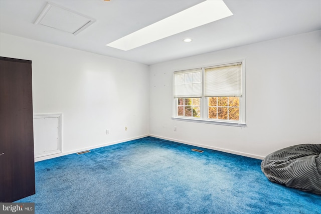 unfurnished room featuring baseboards, a skylight, visible vents, and carpet