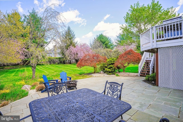 view of patio / terrace featuring a fire pit, outdoor dining space, a wooden deck, and stairs