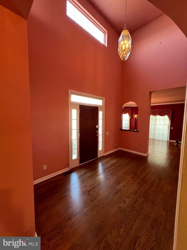 122 Lahinch Ct, Middletown, DE 19709 - entryway featuring baseboards, a towering ceiling, arched walkways, dark wood-style floors, and a notable chandelier