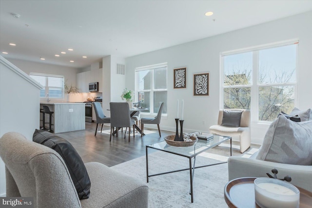 living room with visible vents, baseboards, recessed lighting, and light wood-style floors