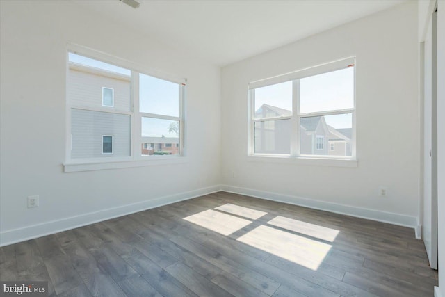 unfurnished room with dark wood-style flooring and baseboards