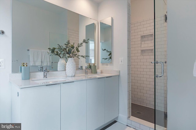full bathroom featuring a stall shower, double vanity, and a sink