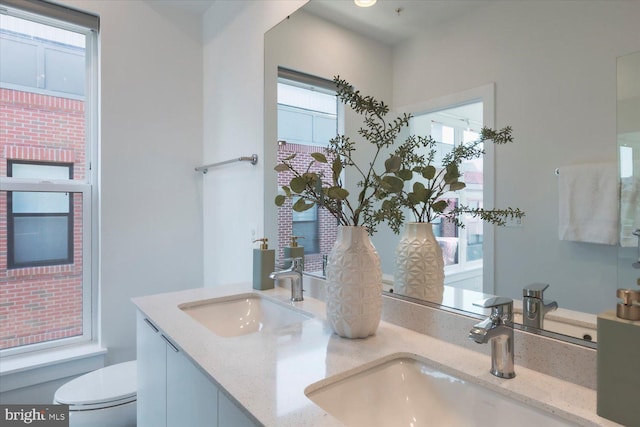 bathroom with a sink, toilet, and double vanity